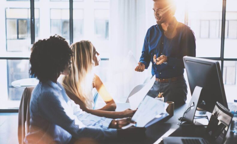 Man speaking to two women sitting behind desk