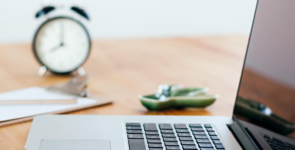 Laptop on table with clock